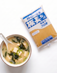Supă miso shiro servită cu lingură renge, lângă punga de pastă miso albă