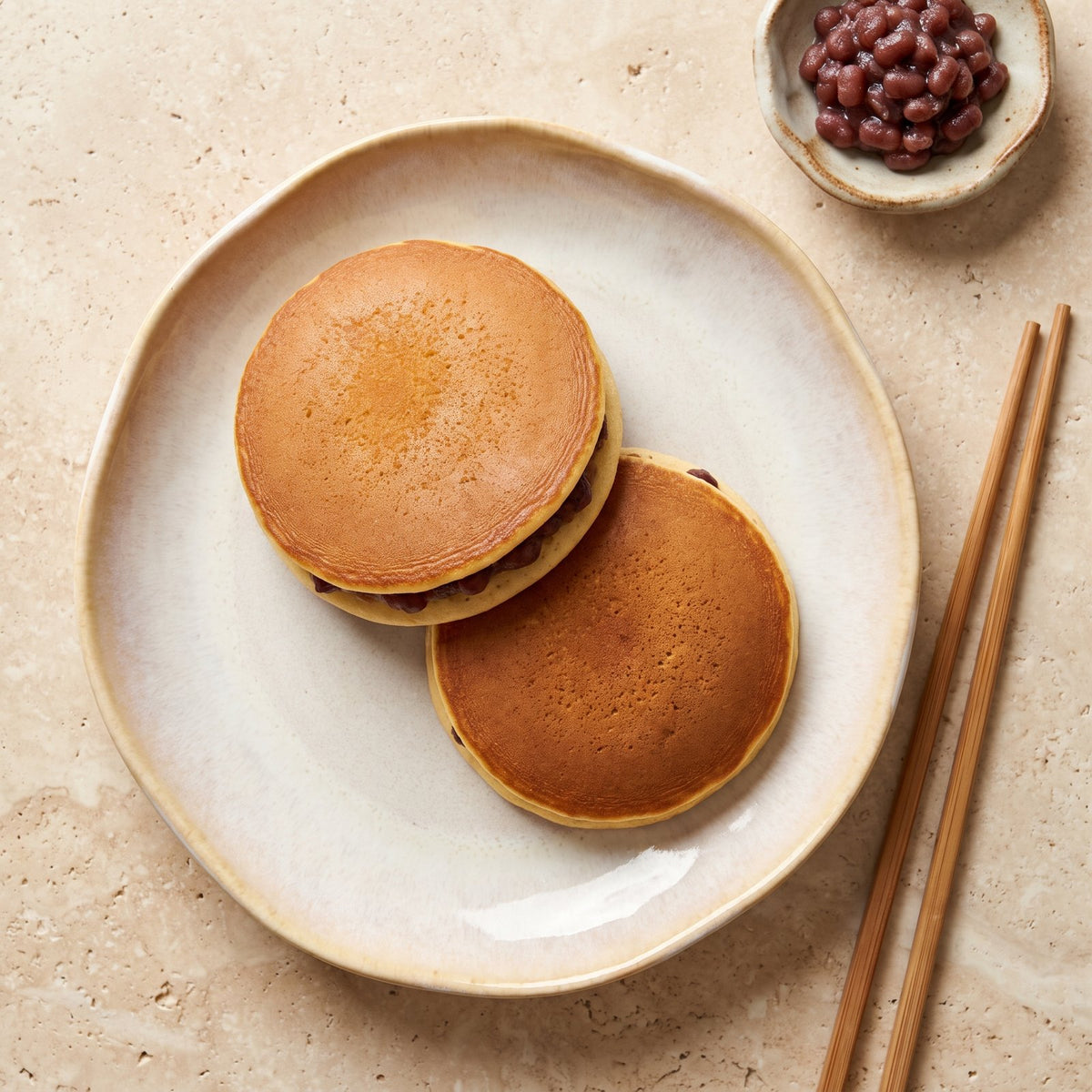Clătite japoneze dorayaki: discuri arămii pufoase suprapuse, umplute cu pastă de fasole adzuki, pe farfurie ceramică