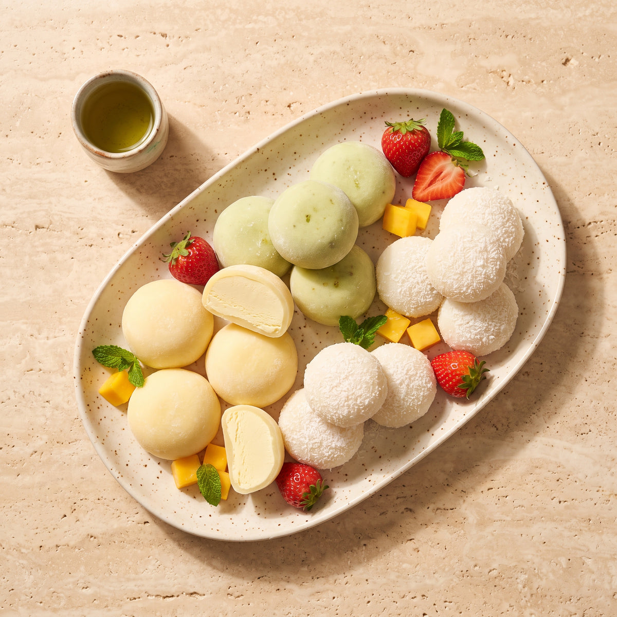Platou de mochi asortat cu mochi cu înghețată, daifuku cu cocos, fructe proaspete și ceai verde