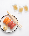 Gari alb servit lângă nigiri sushi, cu plicurile individuale de ghimbir murat